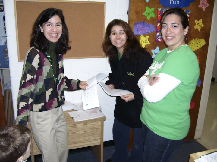 Three preschool teachers looking at paperwork in preparation for a Spanish class