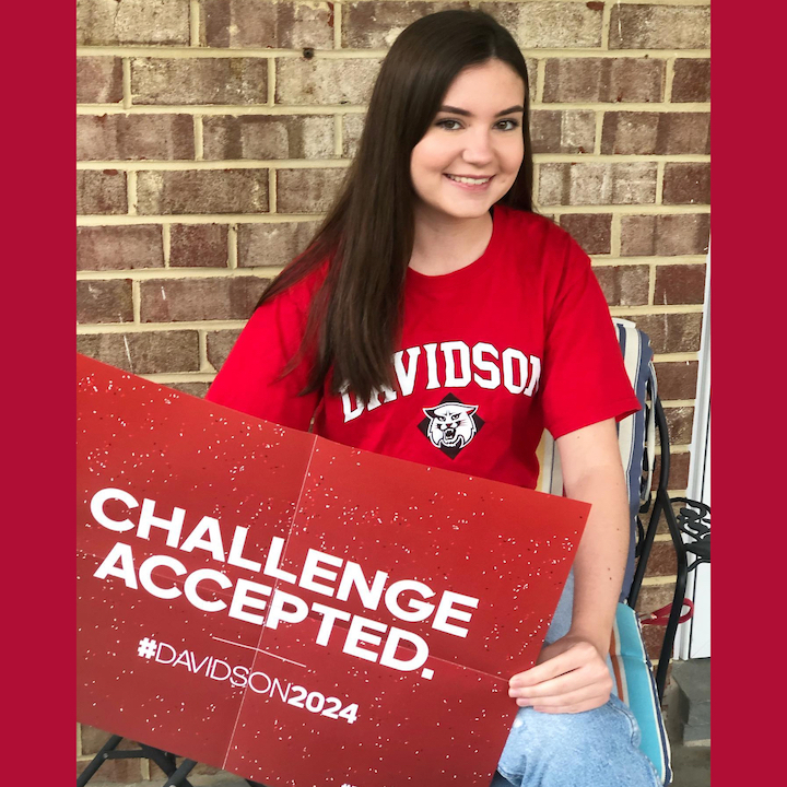 Student wearing college shirt and holding Davidson sign