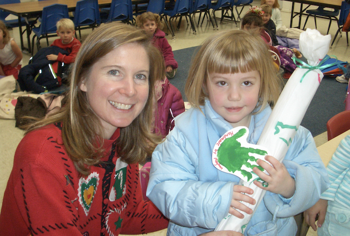Preschool teacher with a student, holding Christmas art project