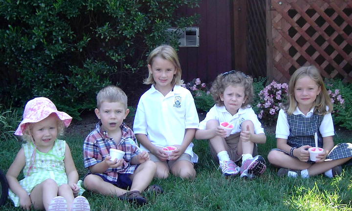 Five children holding Italian ices and sitting in the grass