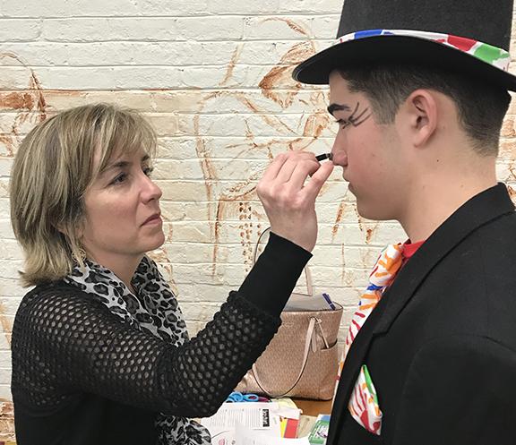 A parent volunteer helps with makeup for 