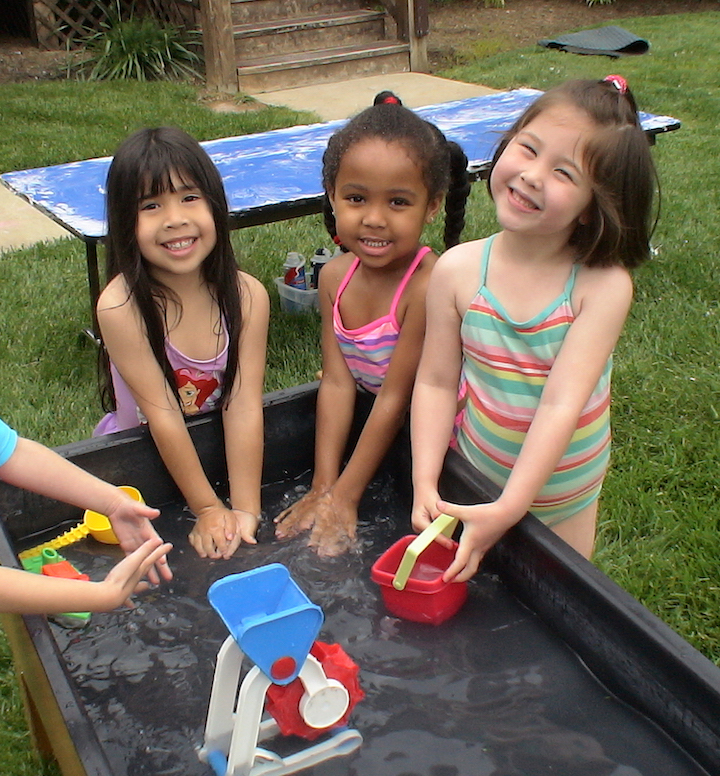 Three preschool girls playing at the water table on Sprinkler Day
