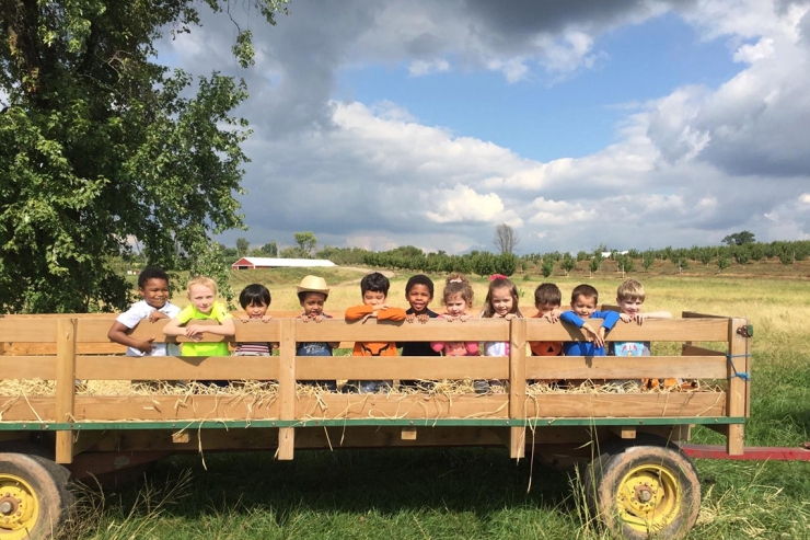 Preschoolers in a hay wagon with heart-shaped cloud above